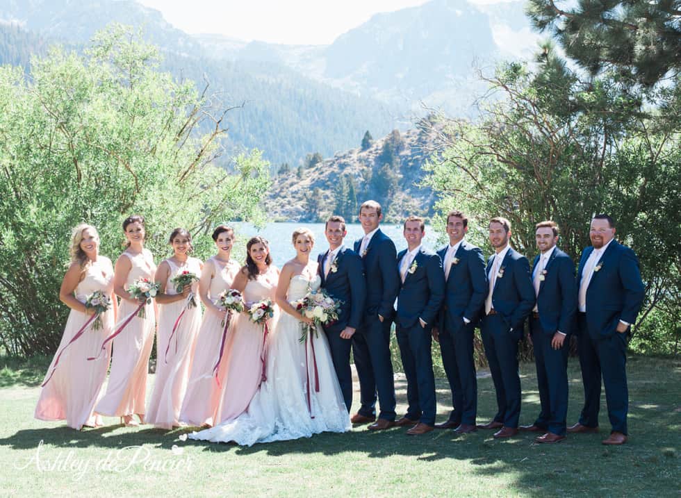 Bridal party standing by a lake